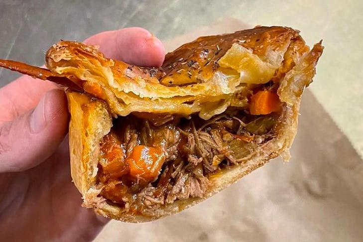 hand holding half-cut meat pie